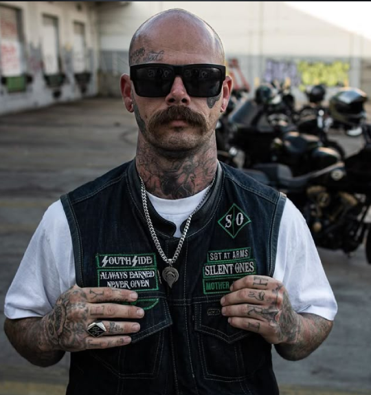 Tough biker wearing sleeveless black leather vest with patches – Biker Vest US